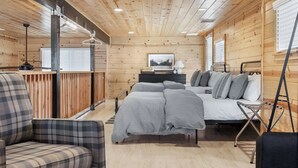 A cozy cabin interior with a bed, a chair, a desk, and a window. - The Pine Loft Family-Friendly Nature Retreat (North Fork)