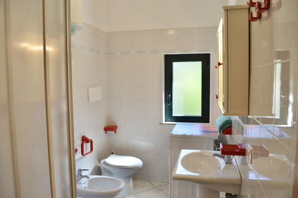 Une salle de bain équipée de toilettes, d’un bidet, d’un lavabo et d’un miroir.