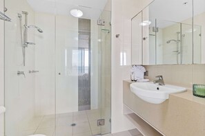 A modern bathroom with a glass-enclosed shower, a white sink, and a large mirror.