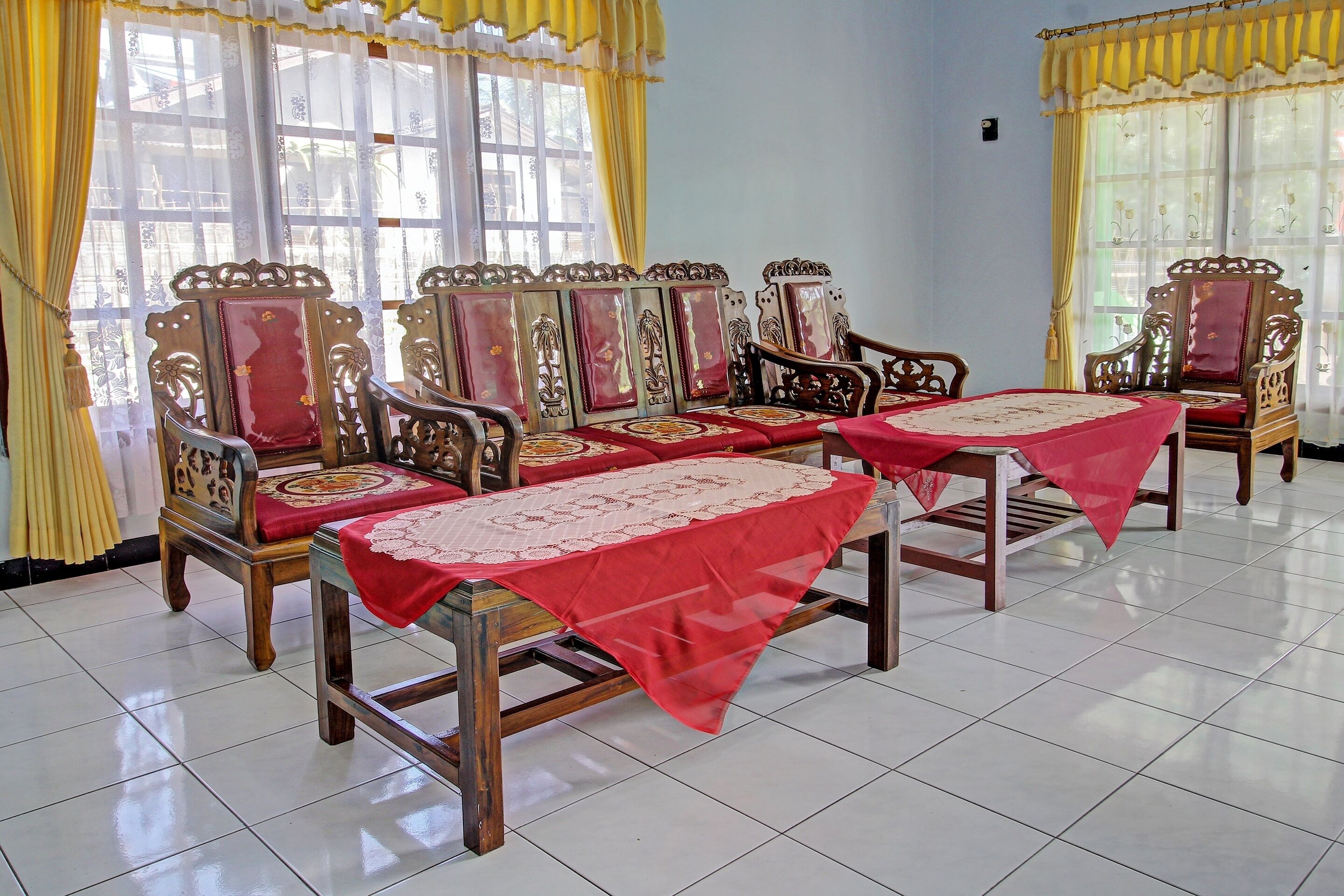 Una habitación con muebles de madera ornamentados, incluyendo sillas y mesas, dispuestos alrededor de un área central.