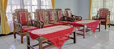 A room with ornate wooden furniture, including chairs and tables, arranged around a central area.