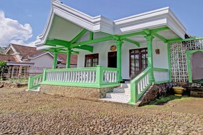 A white building with green accents, a stone foundation, and a staircase leading to the entrance. - Hotel O Desa Wisata Pandean (Dongko)