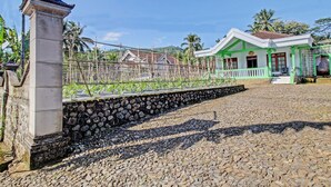 A traditional building with a stone wall and a green-roofed structure in the background. - Hotel O Desa Wisata Pandean (Dongko)