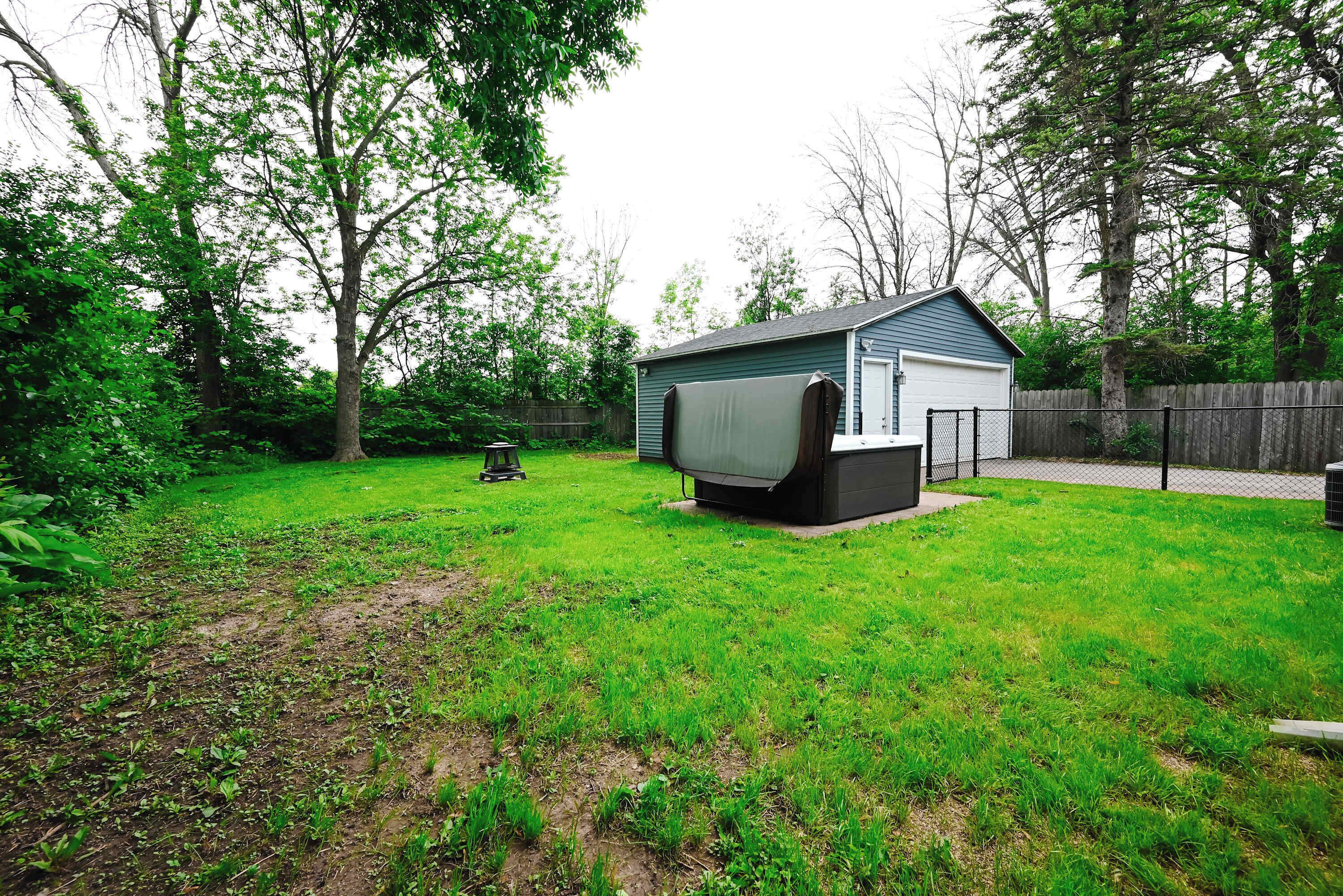A backyard with a shed, a trampoline, and a lawn.