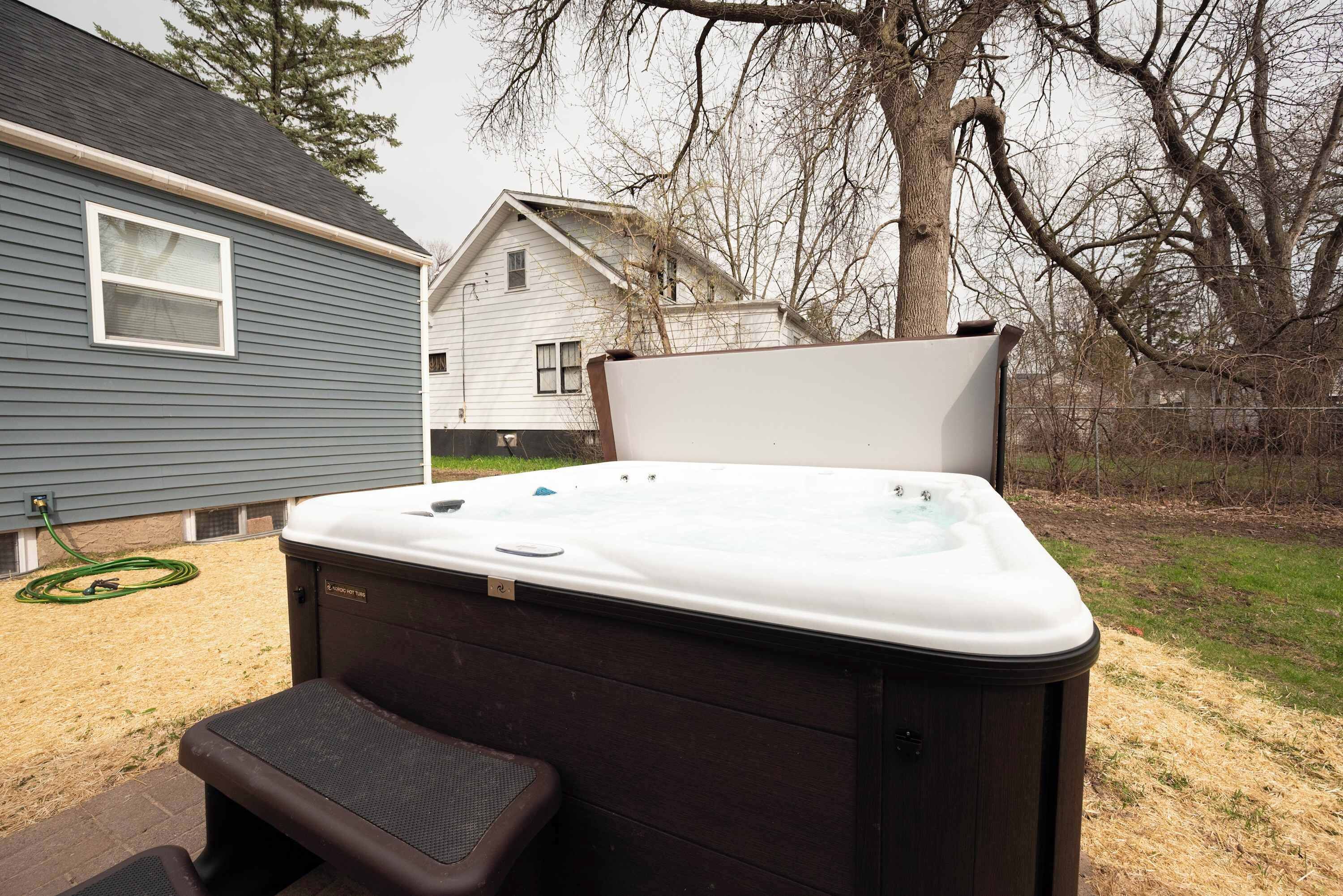 Un jacuzzi en un patio trasero con una casa al fondo.