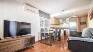 Een moderne keuken met een eethoek, een flatscreen-tv en een bank.
