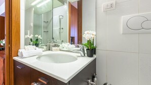 A modern bathroom with a large sink, mirror, and a potted orchid. - Cozy Apartment in St. John - Yellow (Roma)