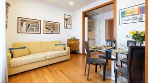 A living room with a sofa, dining table, chairs, and artwork on the walls. - Cozy Apartment in St. John - Yellow (Roma)