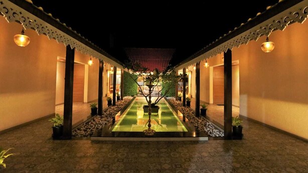 A courtyard with a central water feature, surrounded by walls with decorative railings and evenly spaced lights. - Privystays Jks Private Villa (Alibag)