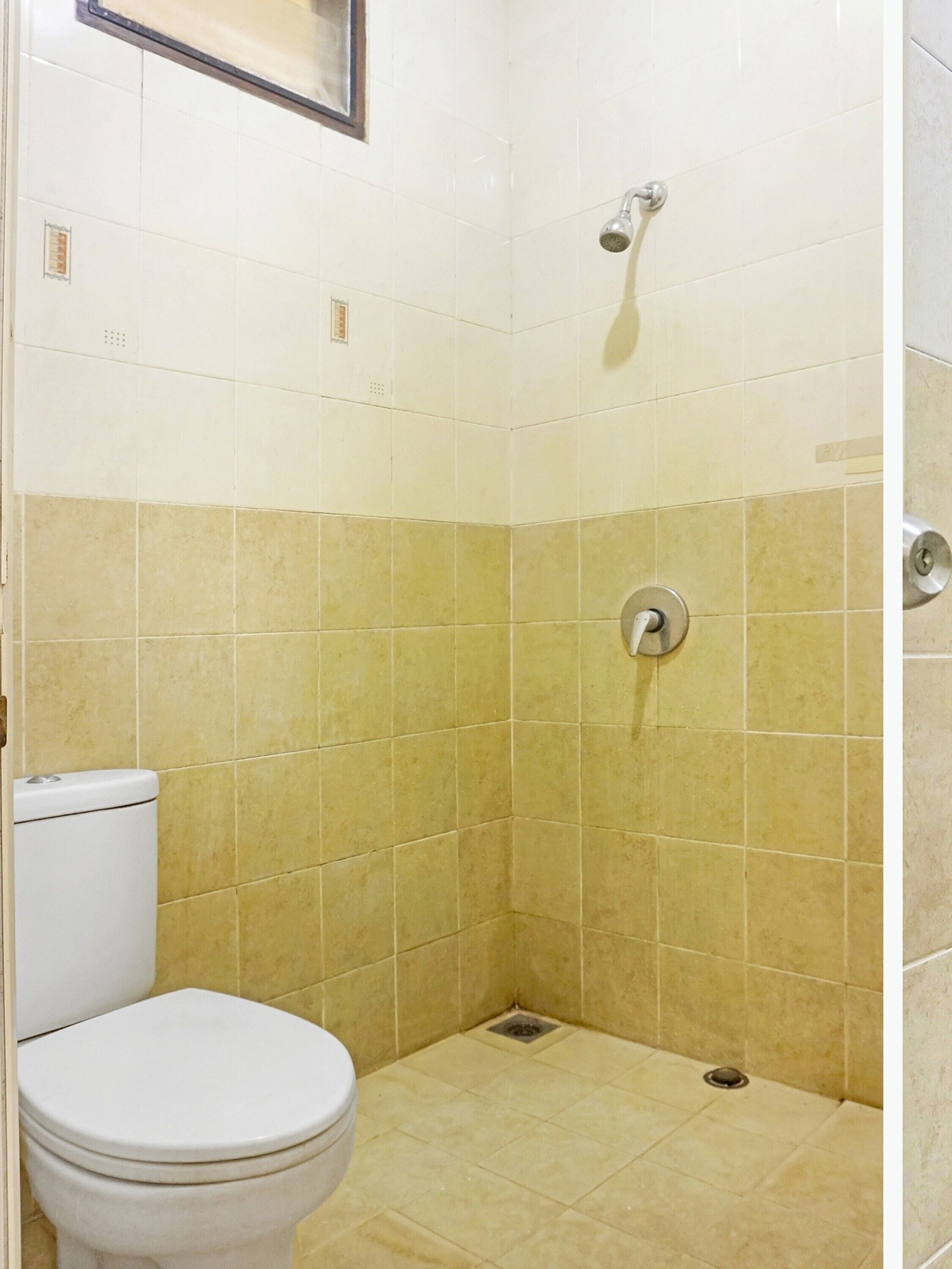 Een kleine, afgesloten douchecabine met een toilet aan de linkerkant.