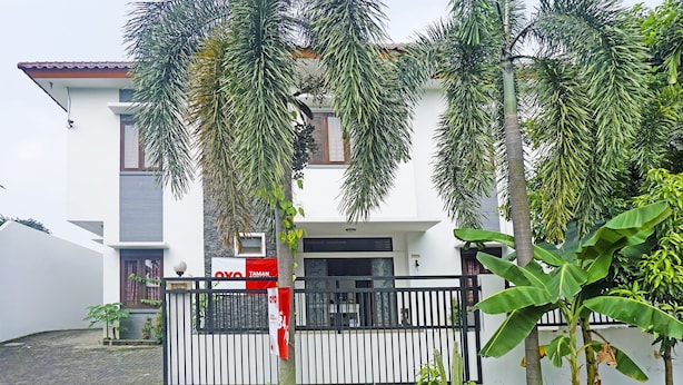 A two-story building with a white facade, a black metal fence, and a red banner. - OYO 91349  Karawaci Taman Permata 3 (Curug)