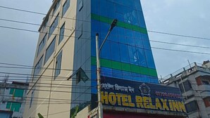 A modern hotel building with a glass facade and a sign for 'HOTEL RELAXINN' at the bottom. - Hotel Relax Inn (Sylhet)