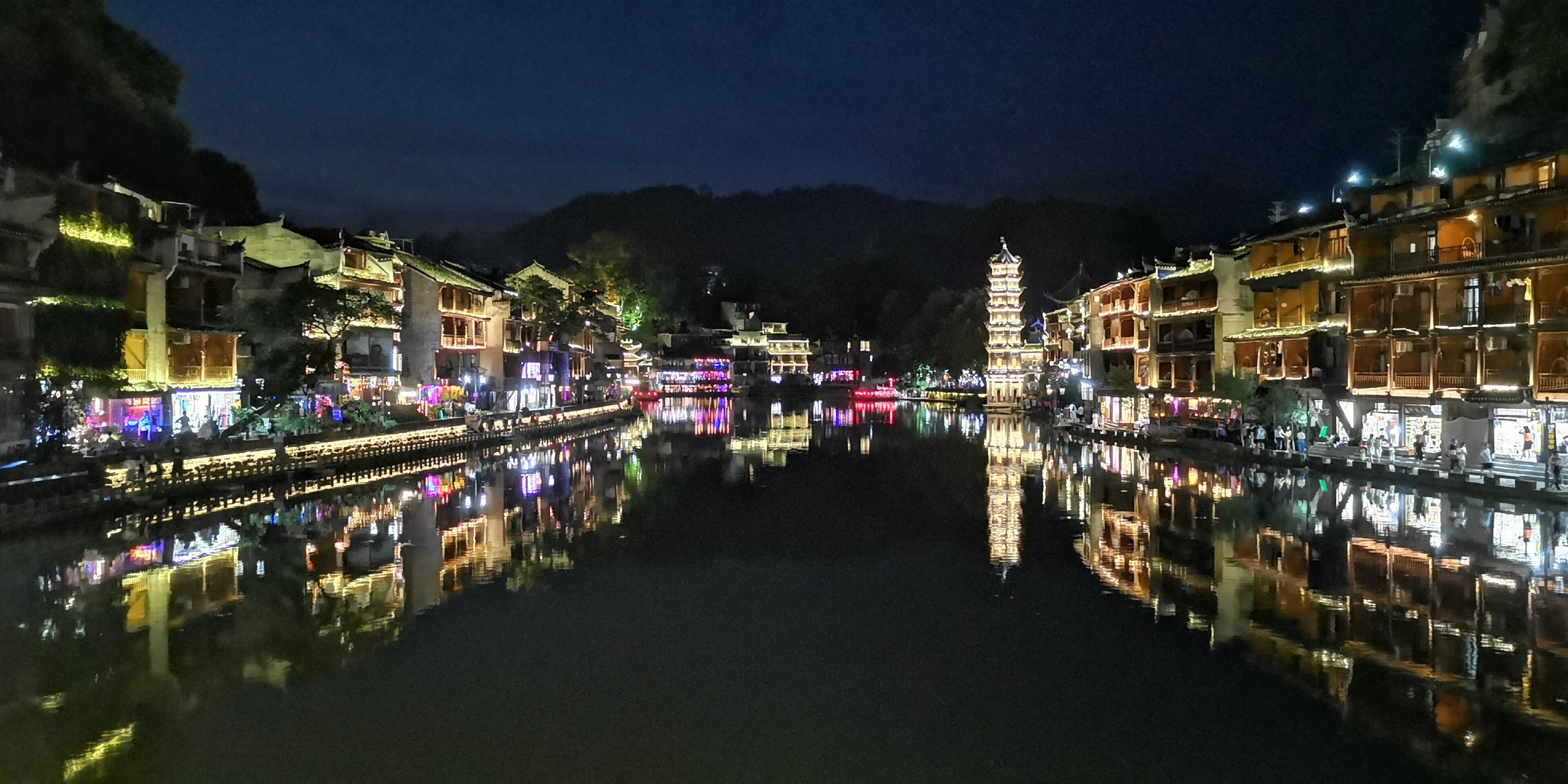 A traditional building with a reflection in the water, surrounded by other structures.