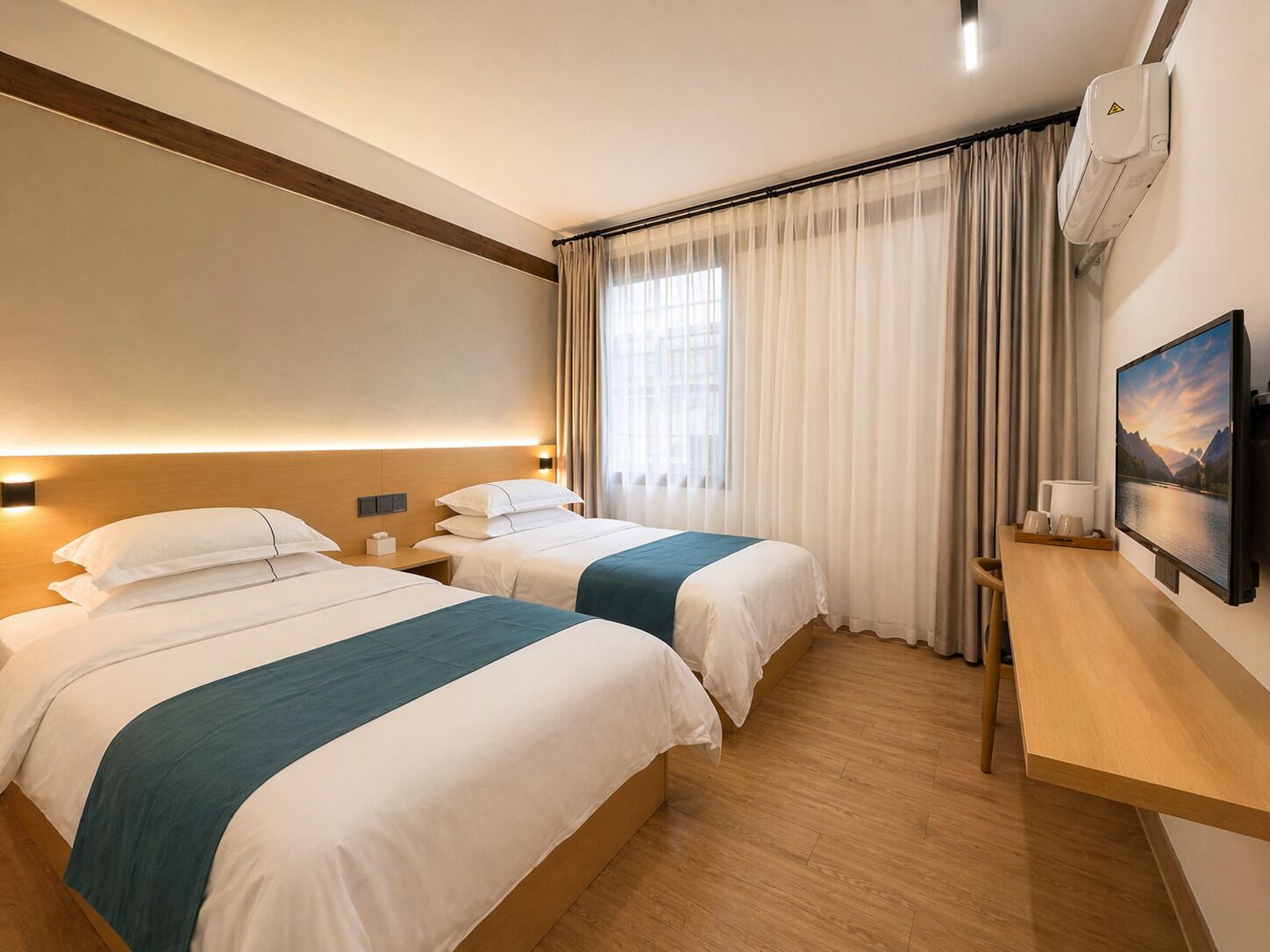 A hotel room with two beds, a desk, a TV, and a window with curtains.