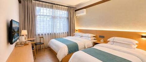 Une chambre d’hôtel avec deux lits, un bureau avec une chaise, une télévision et une fenêtre avec des rideaux.