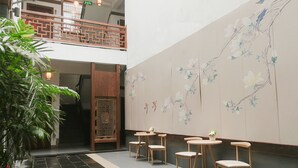 Eine Lobby mit traditioneller chinesischer Wandmalerei, Holzstühlen und einer Treppe.
