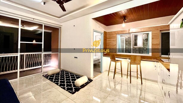 A modern kitchen with a wooden countertop, two bar stools, and a ceiling fan.