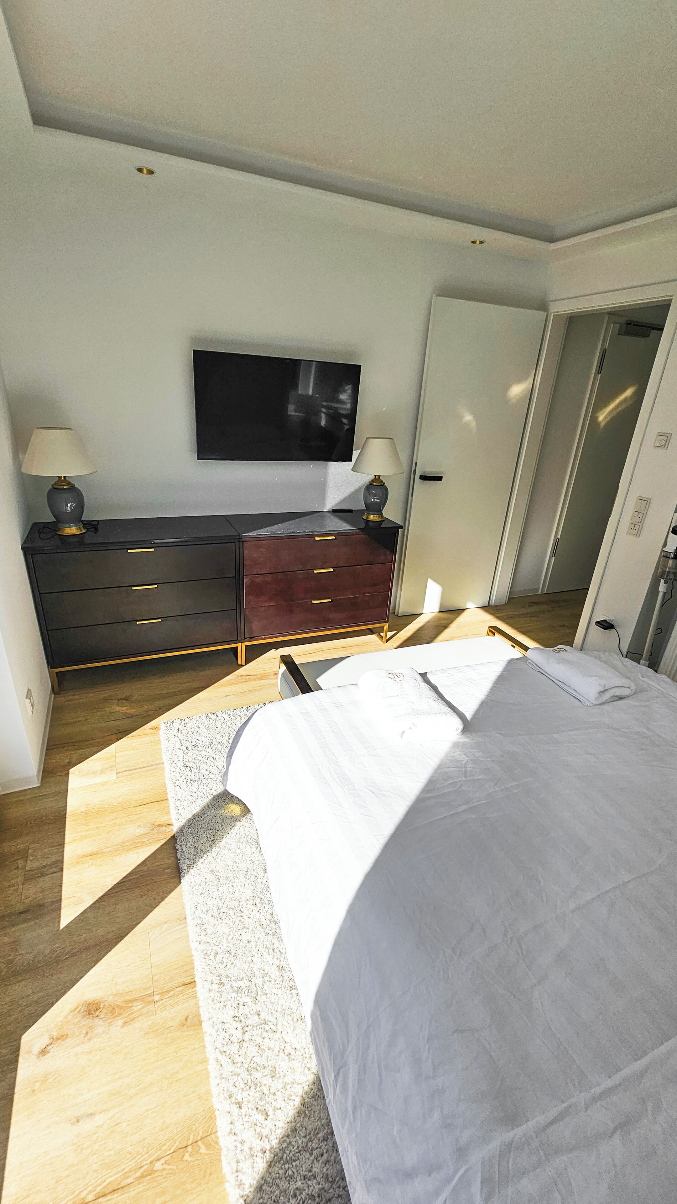 Ein Schlafzimmer mit einem Bett, einem Schminktisch, einem Fernseher und einer Tür.