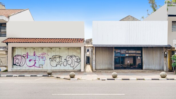 A building with a large garage door and a closed metal shutter door. - OYO 91546 Dewi Sudirman Homestay (Bandung)