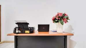 A desk with a laptop, a printer, and a vase with flowers. - OYO 91546 Dewi Sudirman Homestay (Bandung)