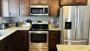 Una cocina moderna con electrodomésticos de acero inoxidable, armarios de madera, encimeras de granito y horno empotrado.