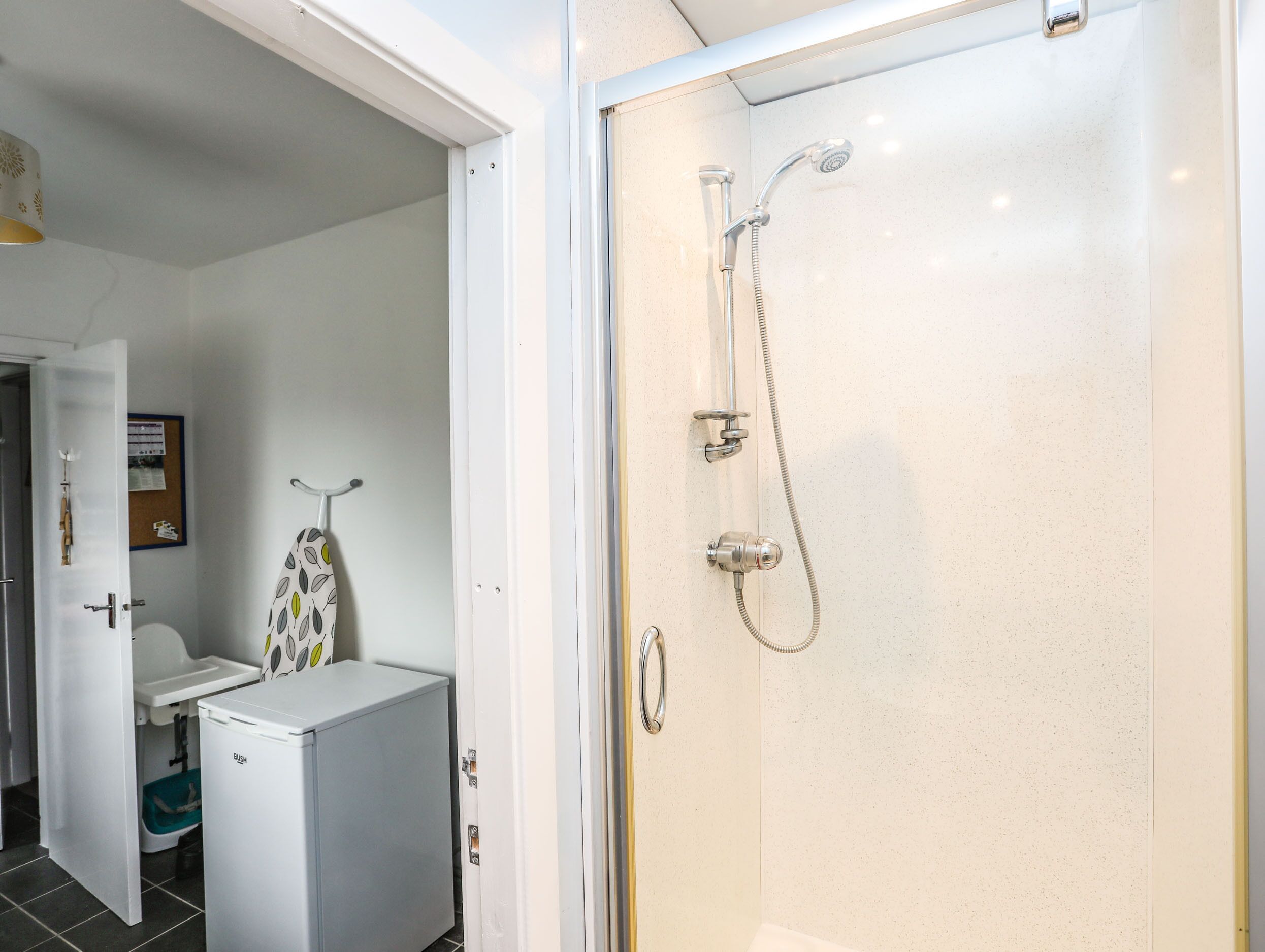 A bathroom with a shower, toilet, and a small refrigerator.