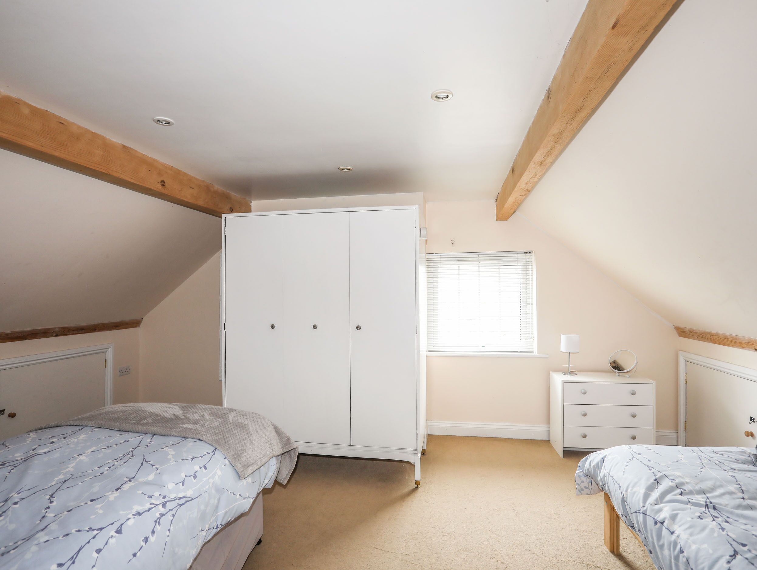 Une chambre avec deux lits, une armoire, une petite table de chevet et une fenêtre.