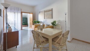 Un área de comedor con una mesa, sillas, un sofá y una planta en maceta.