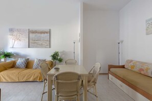 Un salon moderne comprenant un canapé, une table à manger, des chaises et des œuvres d’art accrochées aux murs.