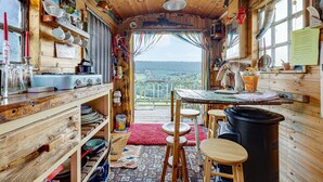 Une cuisine rustique aux murs en bois et dotée d’une grande fenêtre donnant sur une zone boisée.