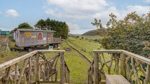 Eine rustikale Holzhütte mit Shell-Logo, ein kleines Gebäude und eine Holzbrücke.