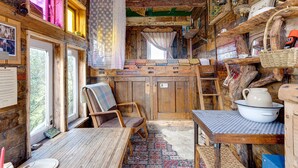 Ein rustikales Blockhaus-Interieur mit Holzwänden, einem Esstisch, einem Stuhl und einer kleinen Küchenzeile.