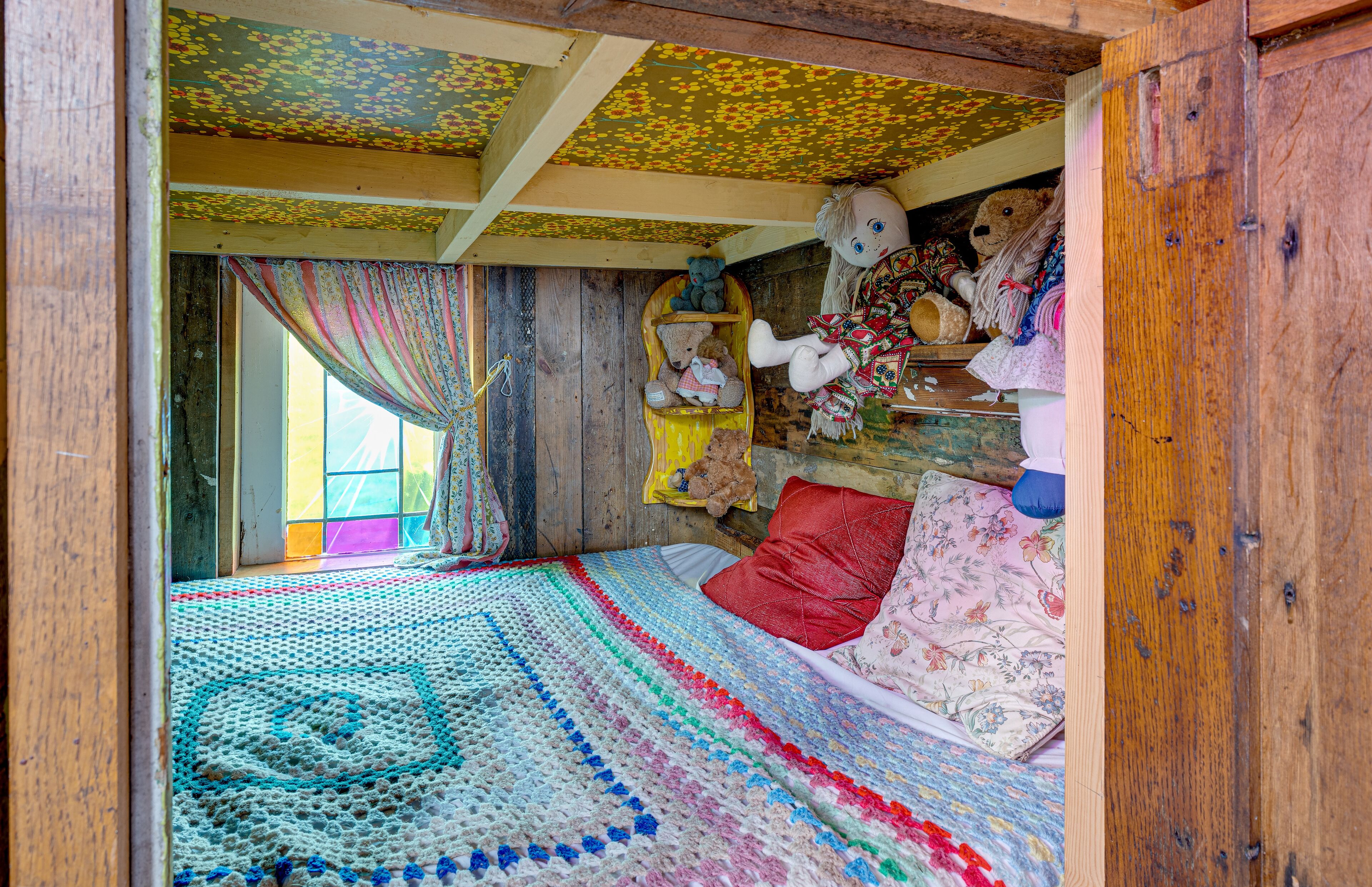 A cozy room with a large bed, a wooden headboard, and a window with curtains.