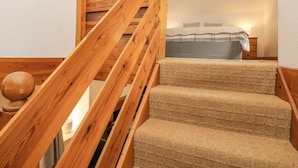 Una scala in legno con una moquette a trama decorativa che porta a una camera da letto.