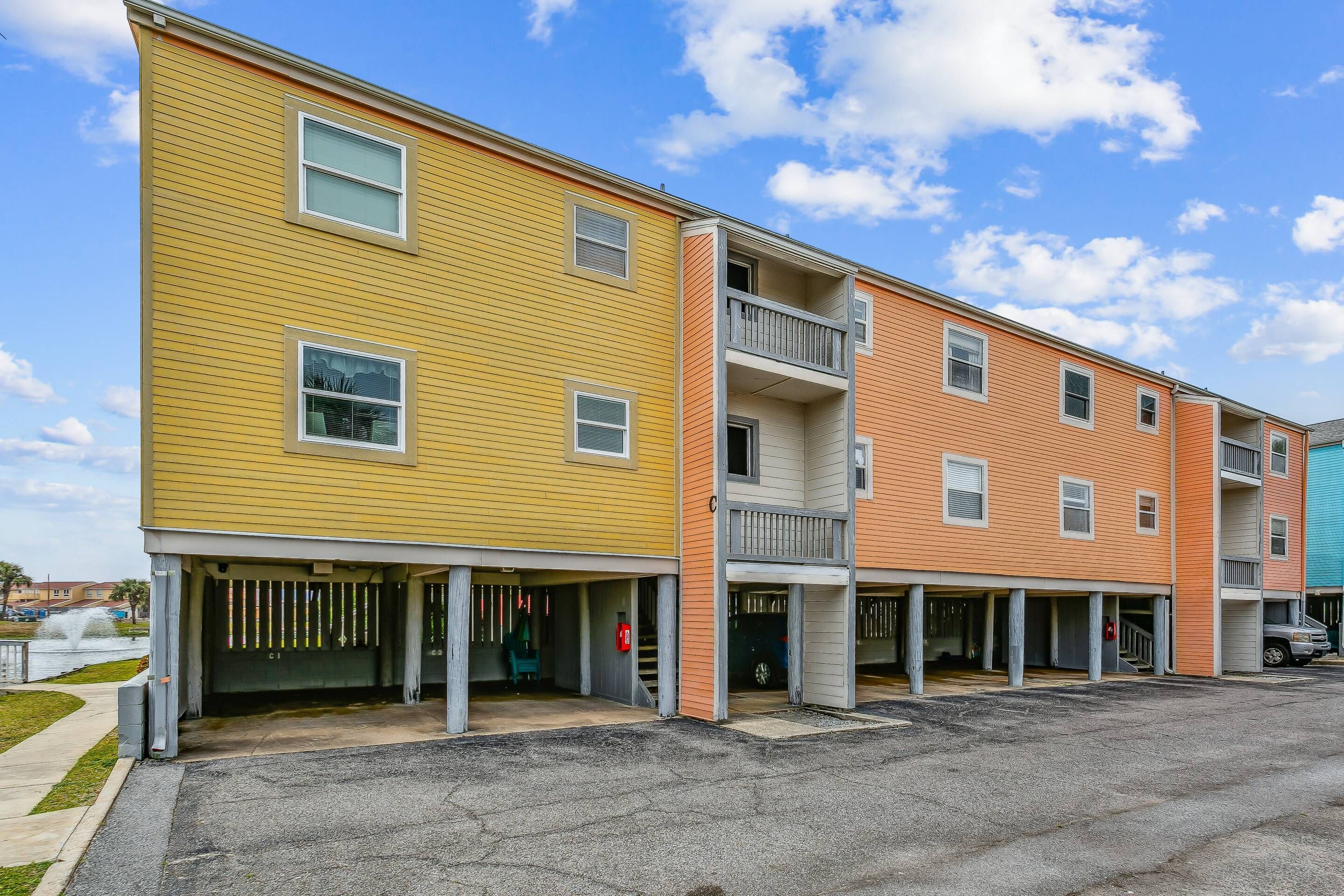 A multi-story residential building with a parking area in front.