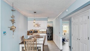 Een moderne keuken met een centraal eiland, houten stoelen en een hangende lamp.