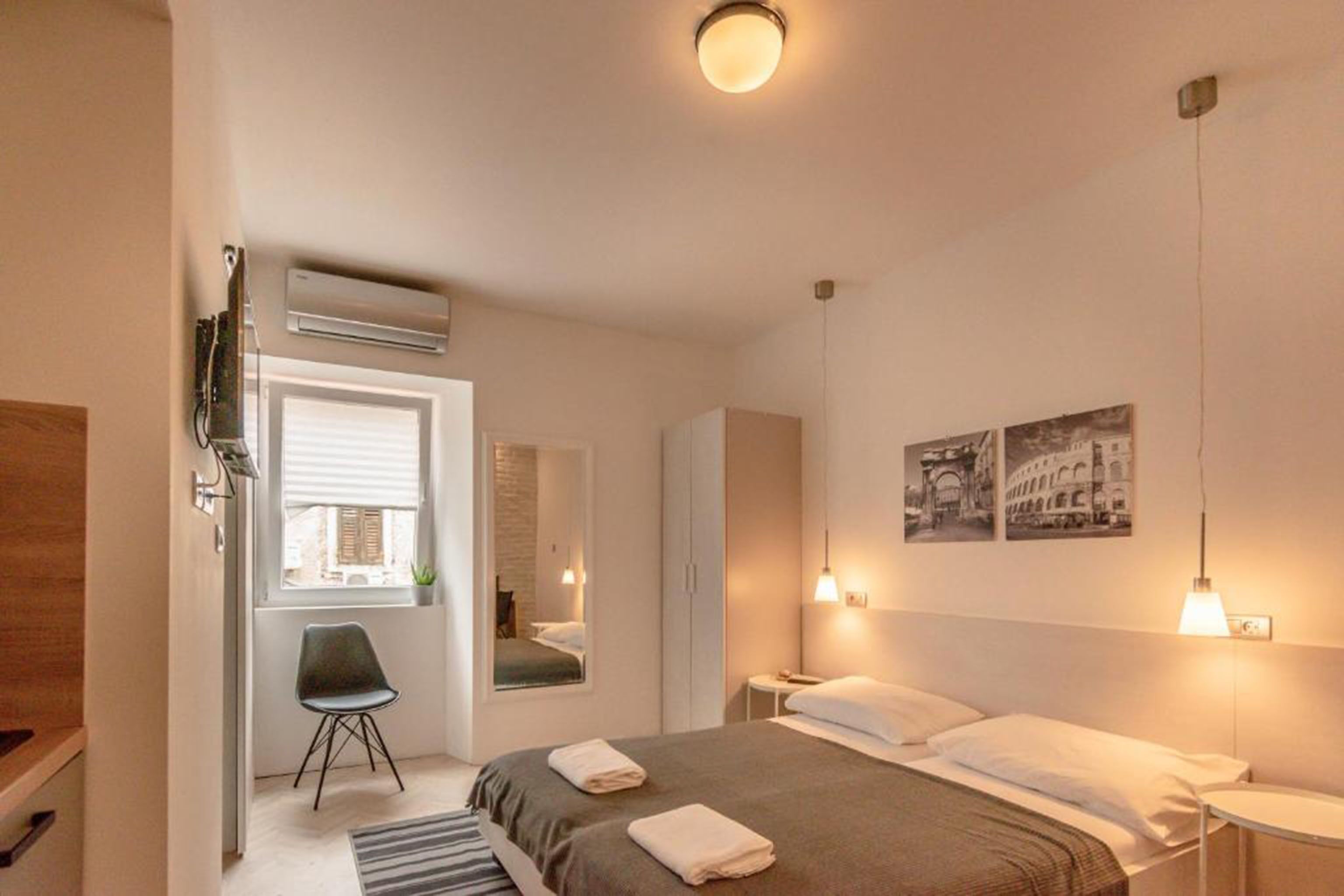 Une chambre d’hôtel moderne, équipée d’un lit, d’une chaise, d’un bureau et d’une fenêtre.