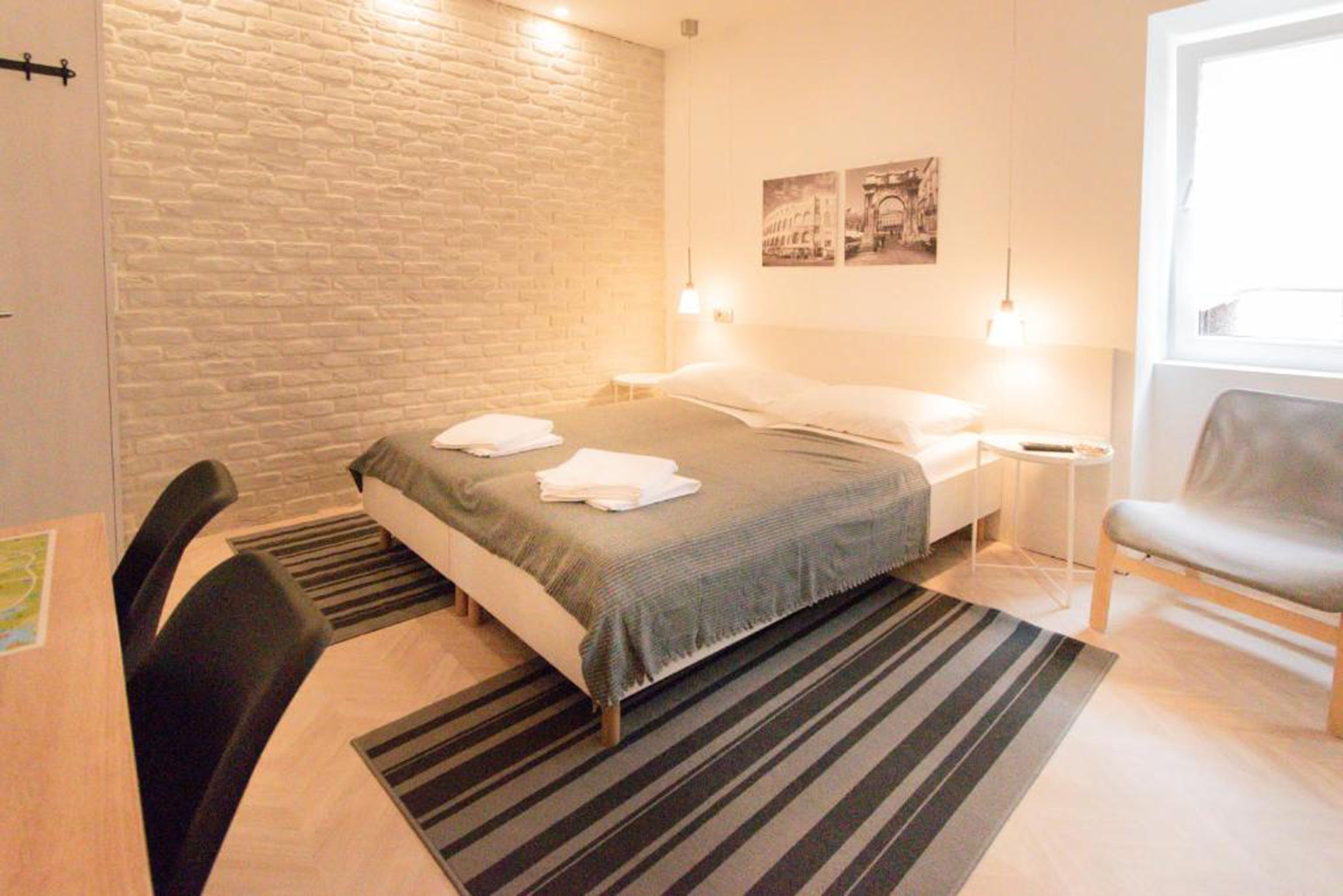 Une chambre à coucher avec un lit, une chaise, une petite table et une fenêtre.