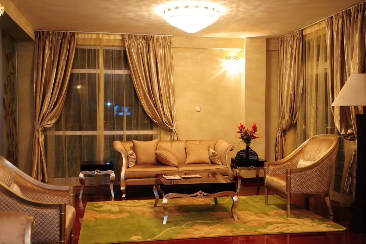 A well-lit living room with a sofa, armchairs, a coffee table, and a chandelier.