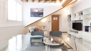 Ein modernes Wohnzimmer mit einem Glastisch, einer Couch und einem Fernseher auf einem weißen Schrank.
