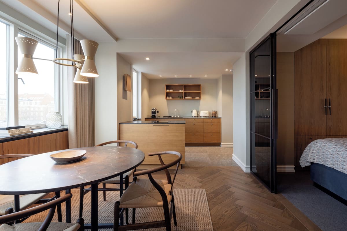 Cocina moderna con isla central, armarios de madera e iluminación colgante.
