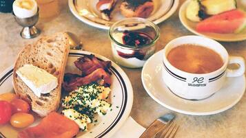 Una mesa de desayuno con platos de comida, una taza de café y un vaso de jugo de naranja.