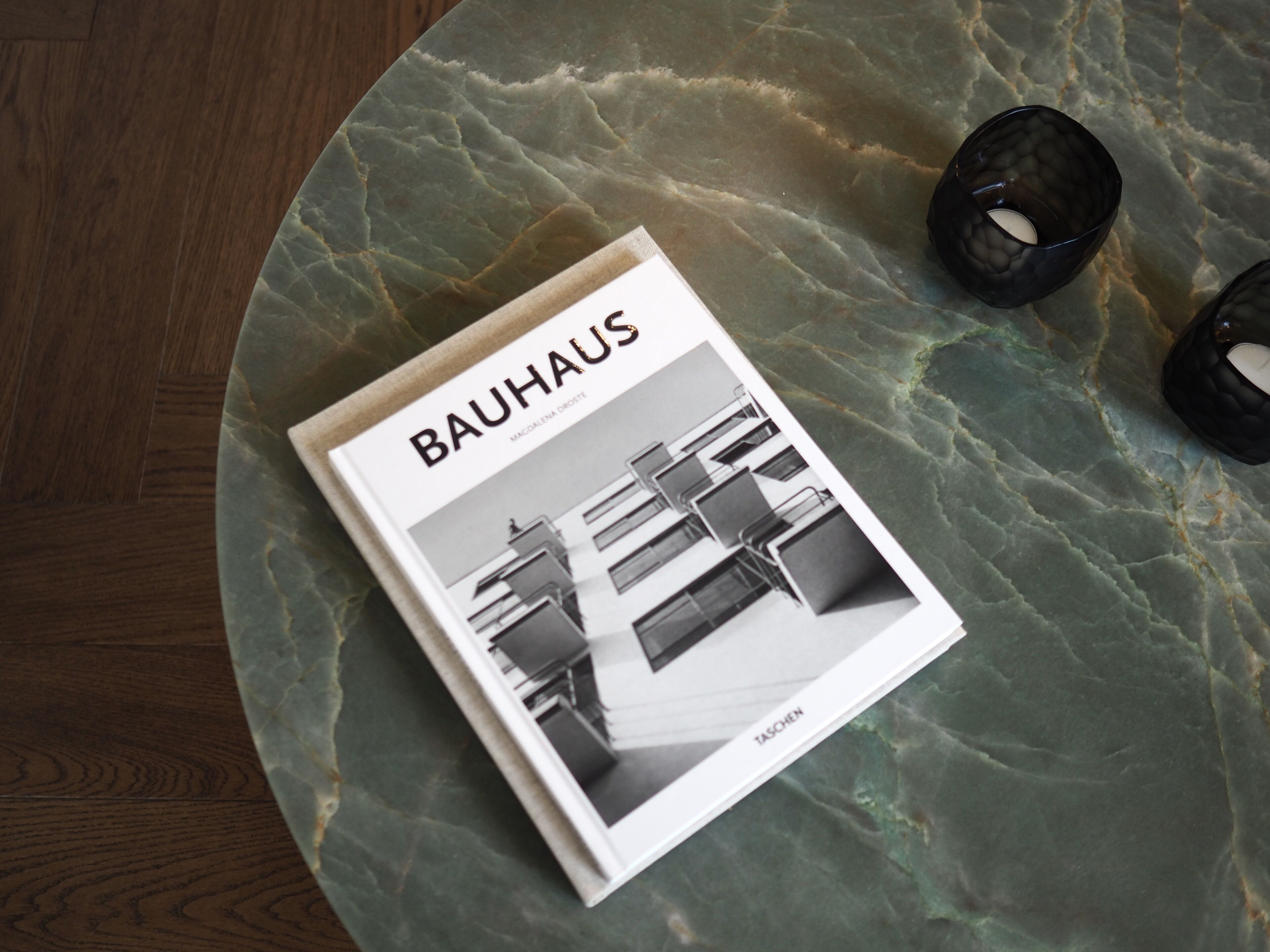A Bauhaus magazine on a marble table with two dark glasses.