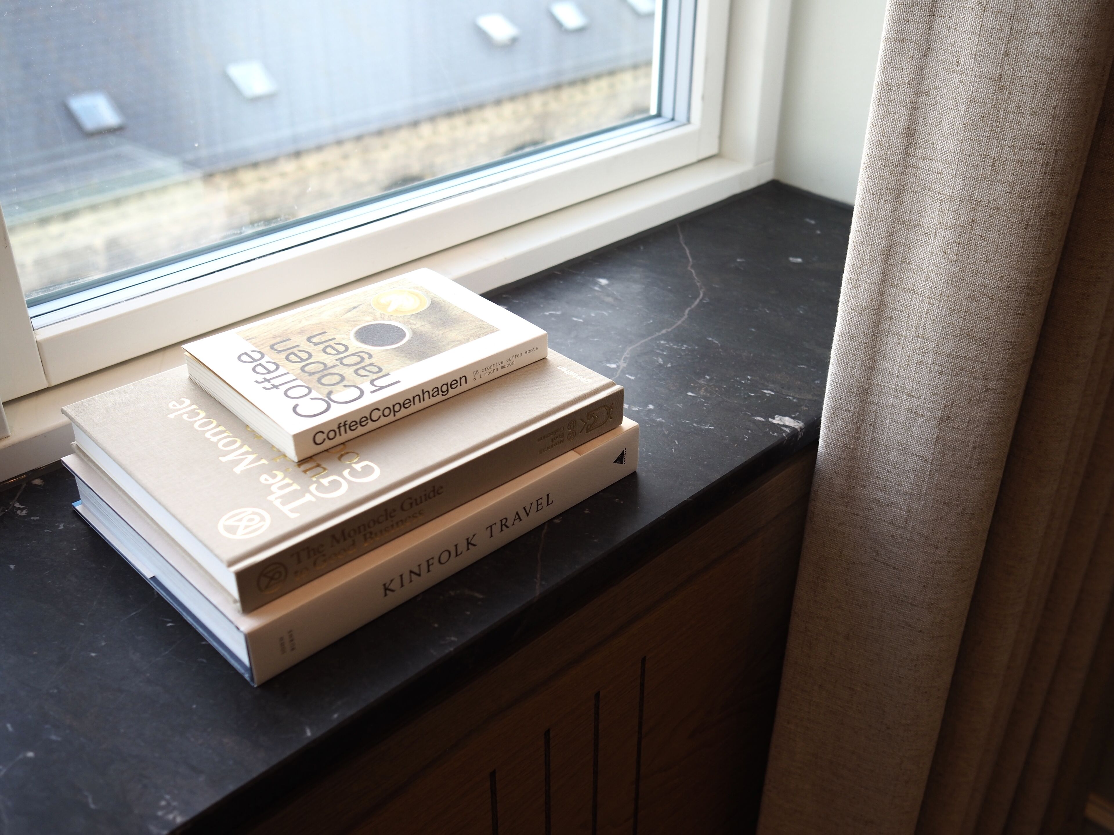A stack of books on a black countertop near a window.