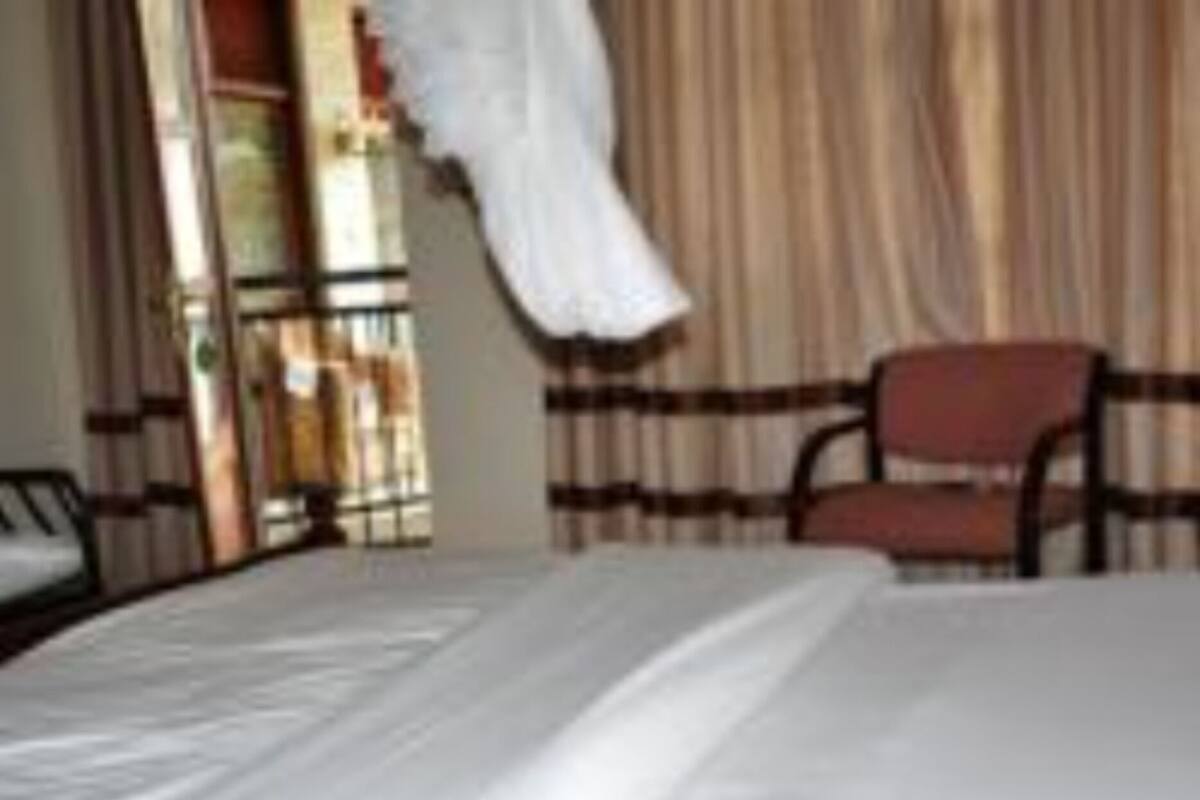A bed with white bedding, a chair, and a curtain in a room.