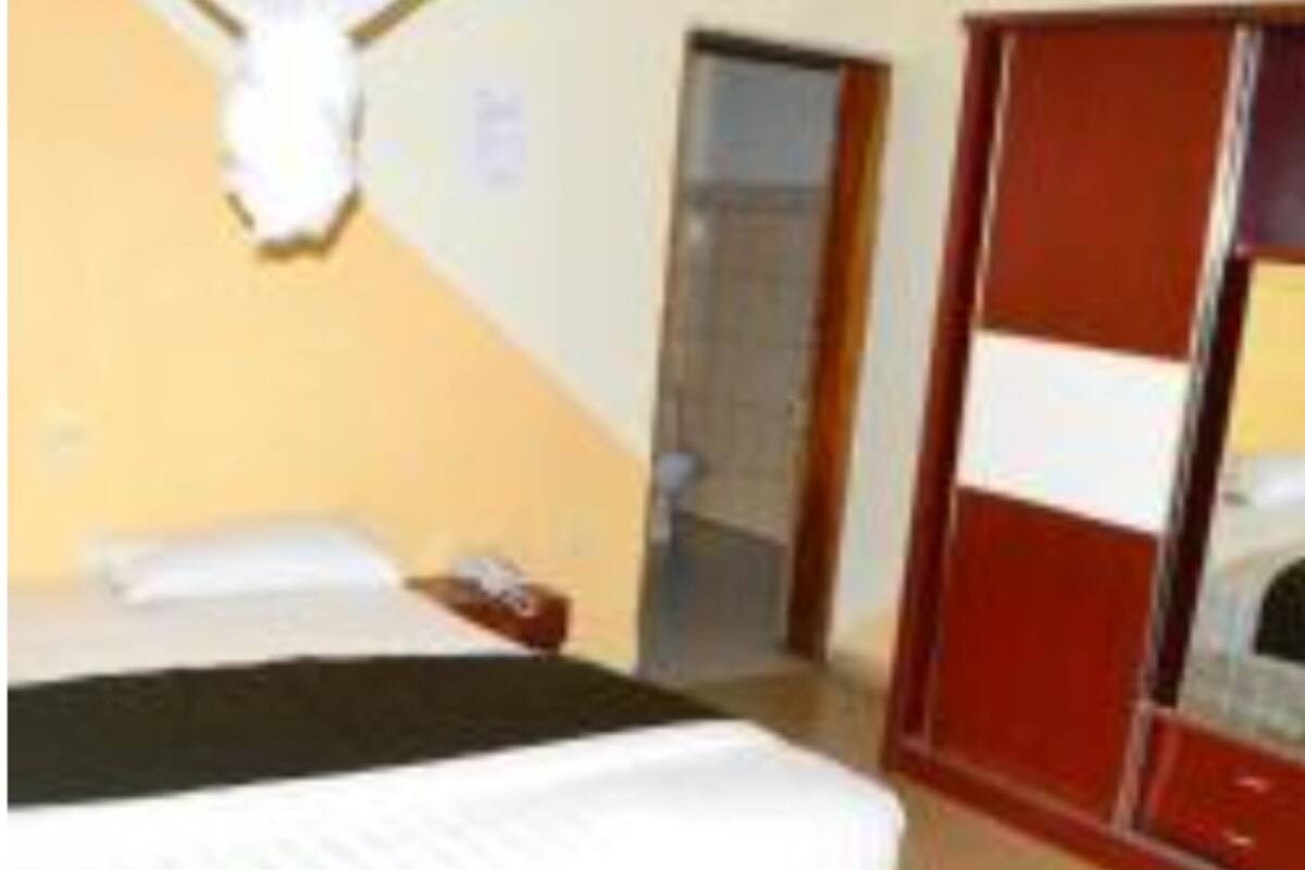 A hotel room with a bed, a wardrobe, and a mirror.