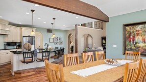 Una cocina amplia con una isla central, comedor con sillas de madera y un cuadro en la pared.
