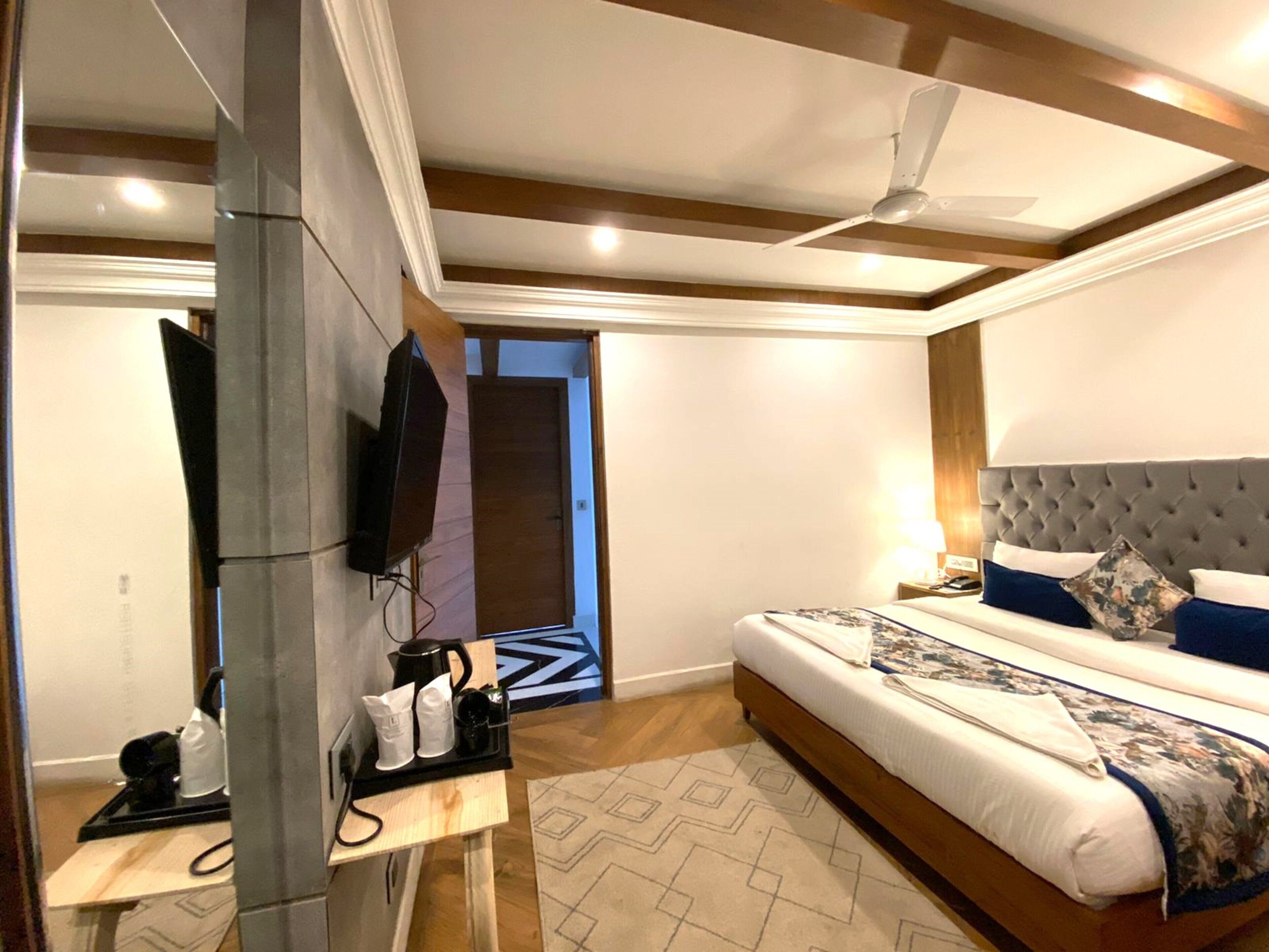Una camera da letto moderna con un letto, una TV, una macchina del caffè e una porta che dà su un'altra stanza.