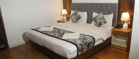 A neatly made bed with a floral bedspread, two bedside tables with lamps, and a wooden headboard.