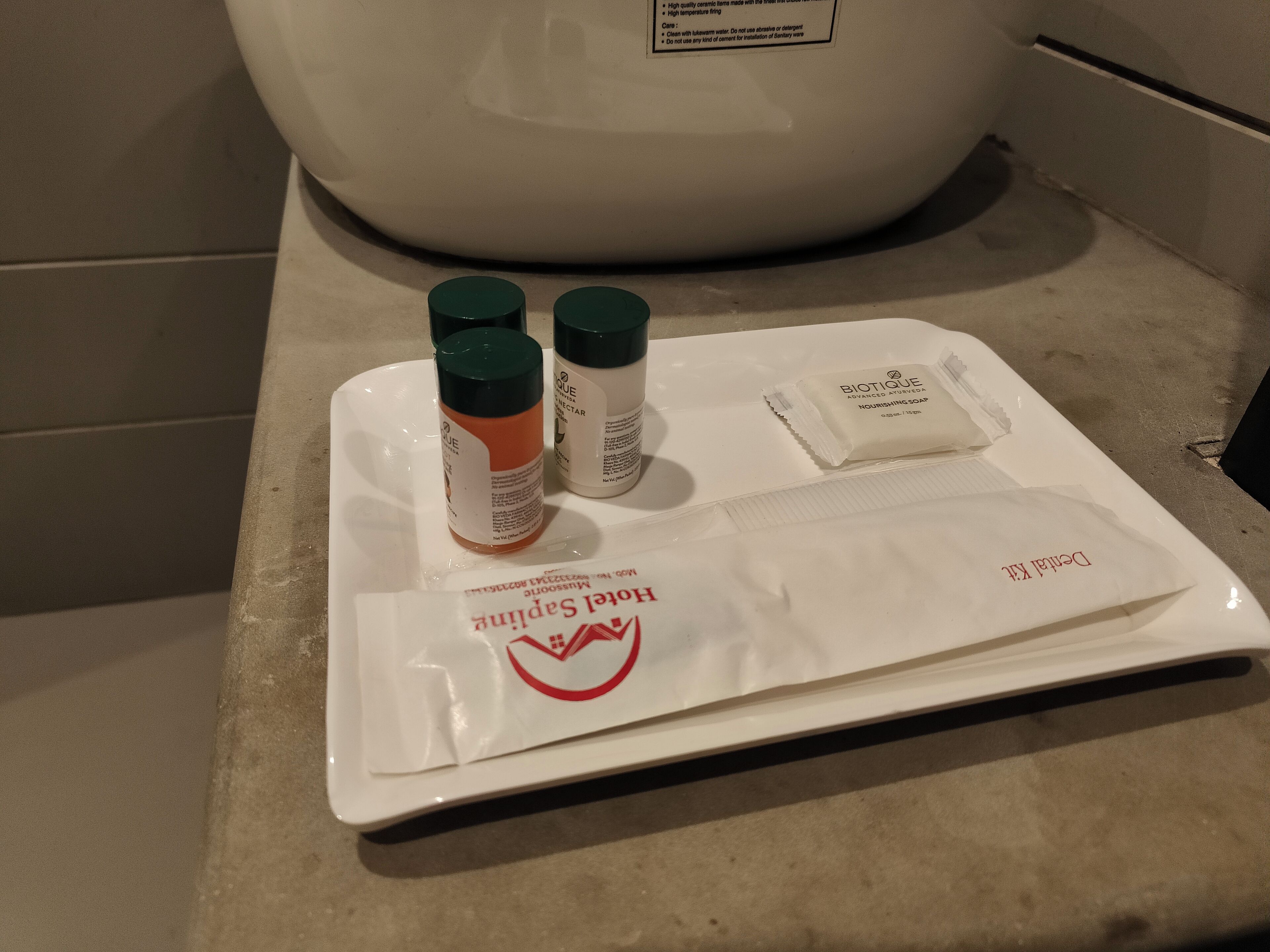 Un plateau contenant des articles de toilette, notamment un flacon de savon nourrissant Biotique Advanced Ayurveda, un flacon de crème Nivea et un paquet de fil dentaire.
